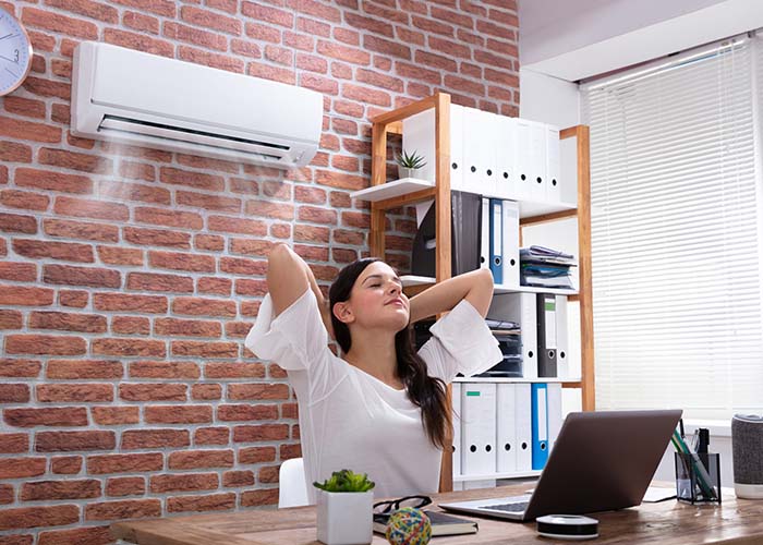 relaxed businesswoman enjoying the cooling of air conditioner in the office