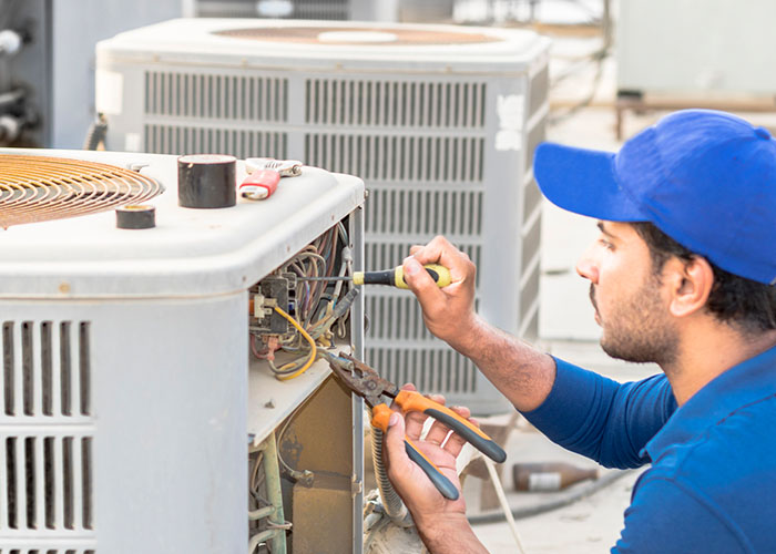 A professional electrician man is fixing the heavy unit of an air conditioner